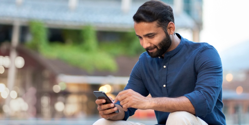 Middle Eastern man in blue shirt holding a cell phone
