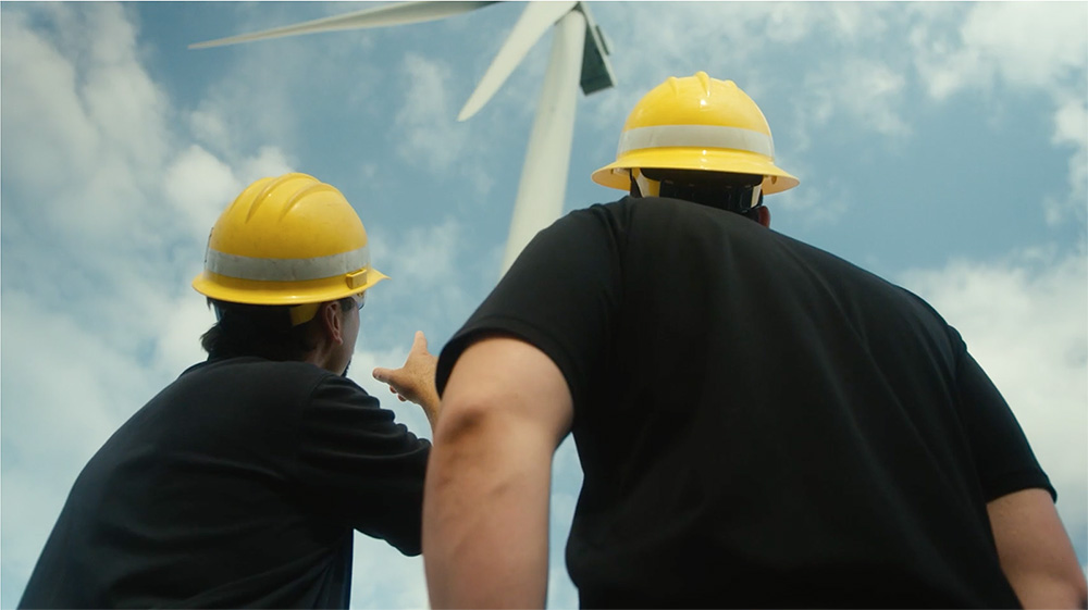 Men looking at windmill wearing hard hats