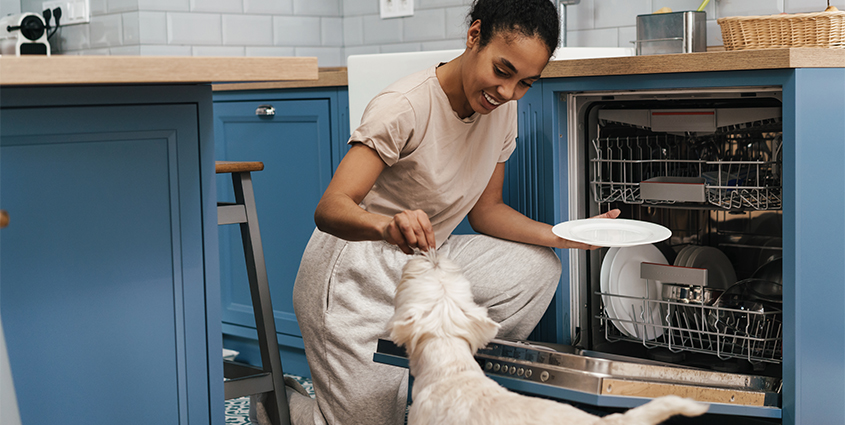 Woman feeding dog by dishwasher