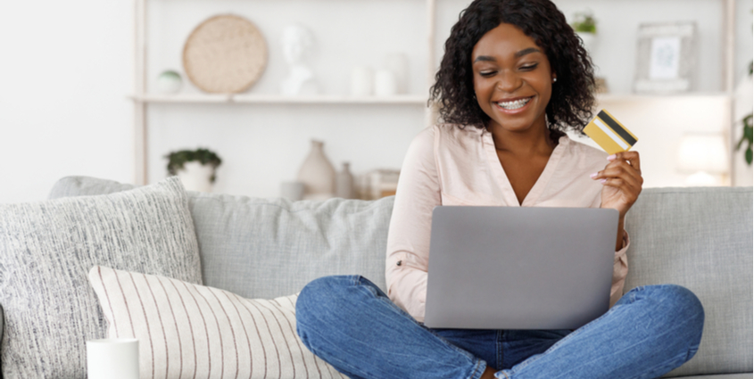 Young woman using laptop and credit card at home to make an online bill payment