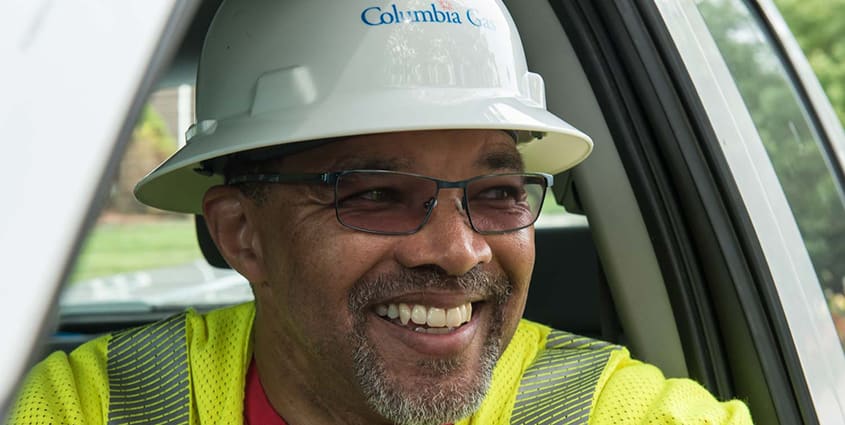African American male Columbia Gas employee smiling wearing white hard had with Columbia gas logo