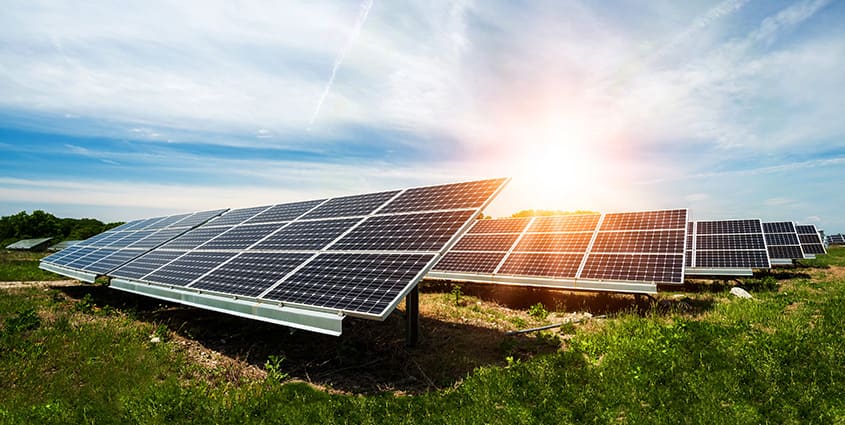 Solar panels in field with the sun reflecting on the panels creating a glare