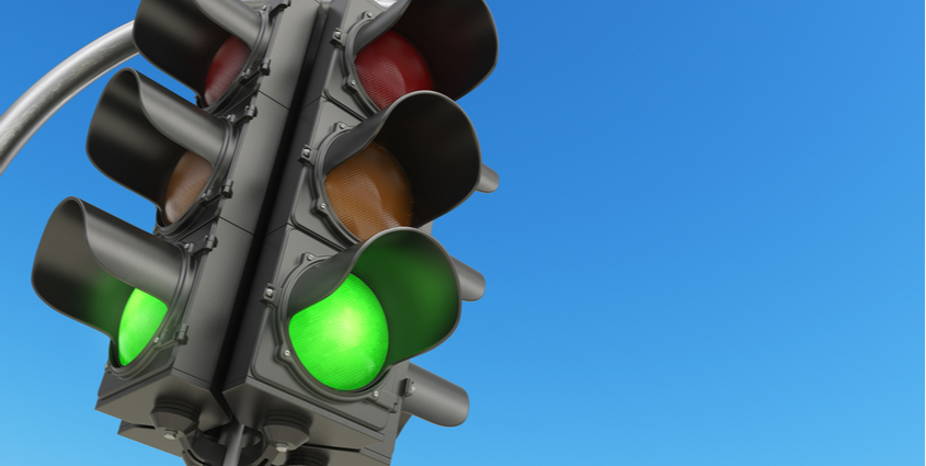 Traffic light with green light illuminated against blue sky